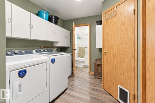 Laundry area with wood-finish flooring, white cabinetry, and a light-colored wall finish - 62202 Rr 444, Rural Bonnyville M.D., AB 