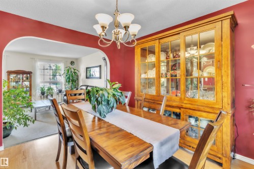Wood-finish flooring with a decorative chandelier and a built-in display cabinet with glass doors - 76 Gariepy Crescent Nw, Edmonton, AB 
