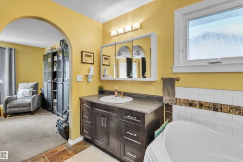 Bathroom featuring a vanity with dark wood-finish cabinetry, a white basin sink, and a mirrored medicine cabinet - 76 Gariepy Crescent Nw, Edmonton, AB 