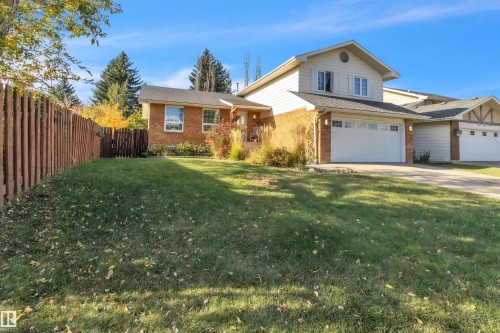 Traditional brick and siding exterior with a multi-pane window, integrated two-car garage, and a paved driveway - 76 Gariepy Crescent Nw, Edmonton, AB 