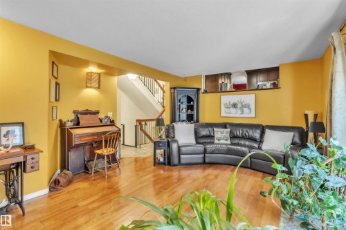 Hardwood flooring throughout, a staircase with wood handrails, and a built-in wall niche with cabinetry - 76 Gariepy Crescent Nw, Edmonton, AB 