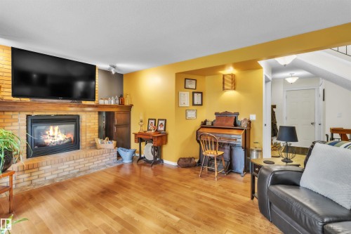 Brick fireplace with a wood mantel, wood-finish flooring, and recessed lighting - 76 Gariepy Crescent Nw, Edmonton, AB 