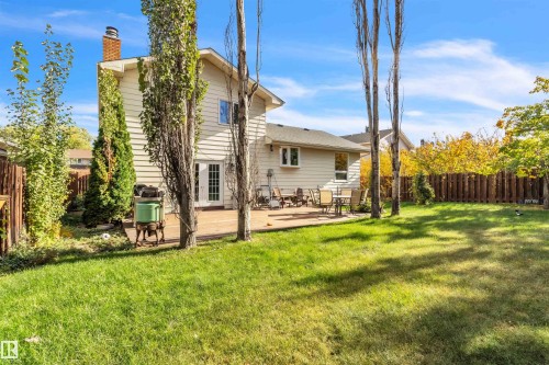 Expansive backyard featuring a green lawn, mature trees, and a privacy fence - 76 Gariepy Crescent Nw, Edmonton, AB 
