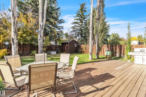 Wood-finish deck with a privacy fence and mature trees - 76 Gariepy Crescent Nw, Edmonton, AB 