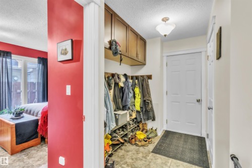 Entryway featuring wood-finish cabinetry, a built-in coat rack, and tiled flooring - 76 Gariepy Crescent Nw, Edmonton, AB 