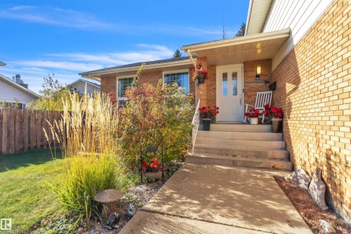 Brick exterior featuring a covered entry, concrete steps, and a white entry door with glass inserts - 76 Gariepy Crescent Nw, Edmonton, AB 