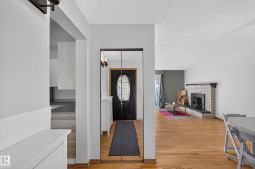 Brick fireplace with black hearth, wood-finish flooring, and mirrored closet doors - 23 Clearwater, Devon, AB 