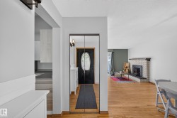 Brick fireplace with black hearth, wood-finish flooring, and mirrored closet doors - 