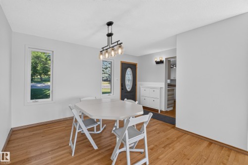 Wood-finish flooring with a contemporary chandelier and white trim windows - 23 Clearwater, Devon, AB 