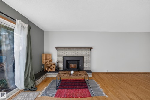 Wood-finish flooring, brick fireplace with a wood-burning insert, and a sliding glass door - 23 Clearwater, Devon, AB 