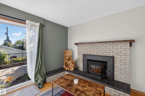 Brick fireplace with a dark wood mantel and a black wood-burning insert - 23 Clearwater, Devon, AB 