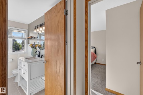 Bathroom featuring a white vanity with integrated sink, matte black faucet, decorative wall mirror, and modern light fixture - 23 Clearwater, Devon, AB 