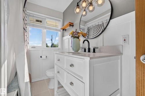 White vanity with polished chrome hardware, black faucet, and light-toned countertop - 23 Clearwater, Devon, AB 