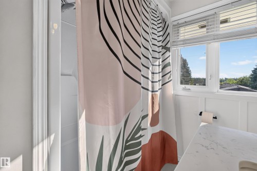 Shower with white surround, white paneled wainscoting, and a window with blinds - 23 Clearwater, Devon, AB 