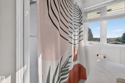 Shower with white surround, white paneled wainscoting, and a window with blinds - 