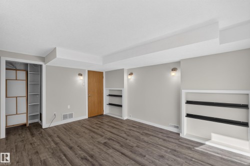 Wood-finish flooring, recessed wall shelving, built-in closet organization, contemporary wall sconces, and a solid wood door - 23 Clearwater, Devon, AB 
