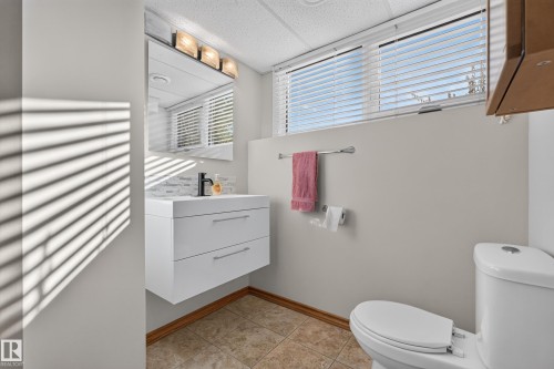 Floating vanity with integrated sink, modern black faucet, tiled backsplash, and vanity lighting - 23 Clearwater, Devon, AB 