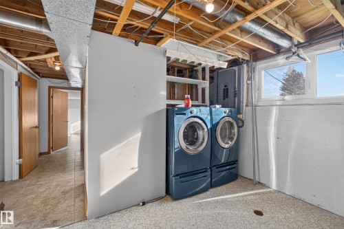 Utility area featuring a washer and dryer, exposed ceiling joists and ductwork, multiple windows, and tile-finish flooring - 23 Clearwater, Devon, AB 