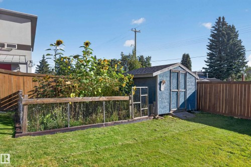 Manicured lawn, wood fencing, blue storage shed, raised garden bed, and mature trees - 23 Clearwater, Devon, AB 