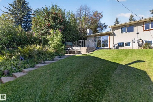 Expansive grassy yard with concrete steps leading to a raised concrete patio with metal railing - 23 Clearwater, Devon, AB 