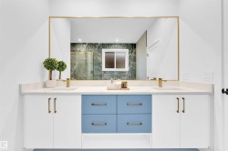 Dual vanity with white cabinetry and blue drawers, quartz countertop, brass fixtures, and a large framed mirror - 