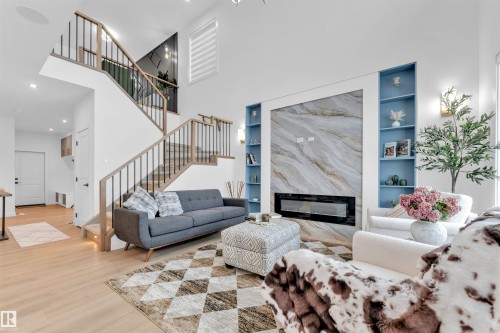 Two-story living area with high ceilings, wood-finish flooring, and a contemporary linear fireplace - 2 Tenuto Link, Spruce Grove, AB 