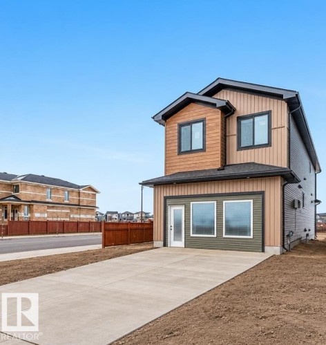 Contemporary exterior featuring multi-toned siding, dark trim, a concrete driveway, and an attached garage with windows - 2 Tenuto Link, Spruce Grove, AB 