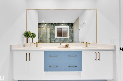Dual vanity with white cabinetry and blue drawers, quartz countertop, brass fixtures, and a large framed mirror - 2 Tenuto Link, Spruce Grove, AB 