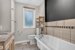 Clawfoot bathtub with chrome fixtures, tile flooring, vanity with stone countertop, and a window with privacy glass - 
