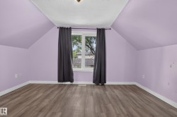 Wood-finish flooring, white trim, and a centered window - 