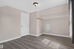 Wood-finish flooring, neutral wall tones, white trim, a flush mount ceiling light, and an integrated closet rod - 