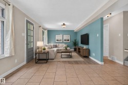 Expansive common area featuring tiled flooring, wood-finish flooring, a French-style door with multiple glass panes, and a decorative wall - 