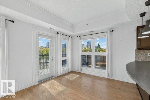 Hardwood-style flooring, white walls, crown molding, double windows, and a glass-paneled door - #306 10232 115 St Nw, Edmonton, AB 