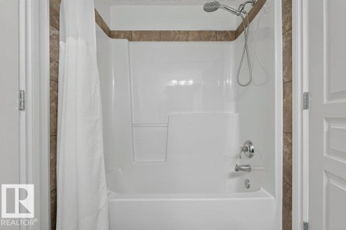 Tub and shower combination with chrome fixtures and brown tiled accents - #306 10232 115 St Nw, Edmonton, AB 