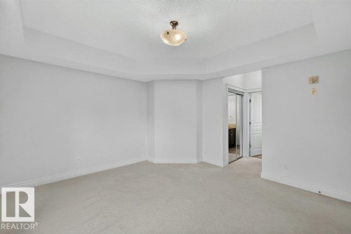 Recessed ceiling detail, neutral wall paint, carpet flooring, flush mount lighting, and a mirrored closet door - #306 10232 115 St Nw, Edmonton, AB 
