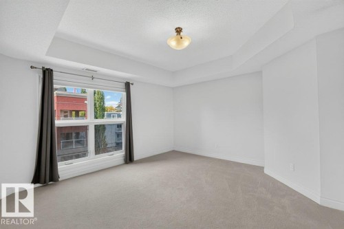 Recessed ceiling detail, ceiling-mounted light fixture, large window, neutral carpeting, and light-toned walls - #306 10232 115 St Nw, Edmonton, AB 