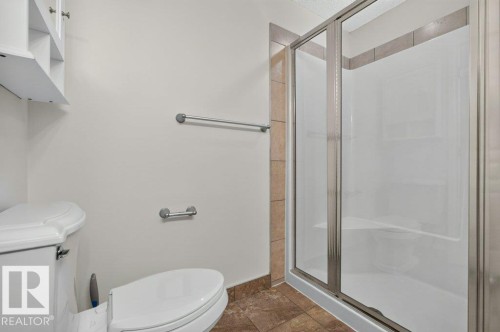 Shower enclosure with sliding glass doors, white acrylic shower surround, and tile accents - #306 10232 115 St Nw, Edmonton, AB 