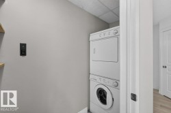 Stackable washer and dryer appliances, light gray wall finish, wood-finish flooring, white paneled door - 