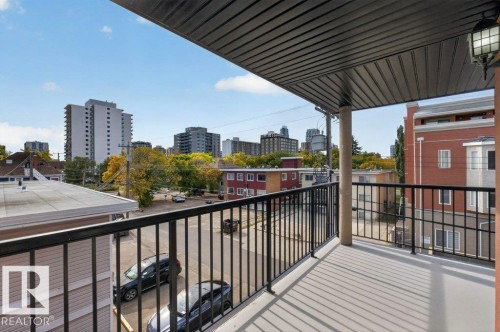 Spacious balcony with black metal railings, a column support, and an overhead light fixture - #306 10232 115 St Nw, Edmonton, AB 