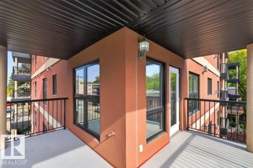 Private balcony featuring a textured exterior, black metal railing, and a glass-paneled door - #306 10232 115 St Nw, Edmonton, AB 