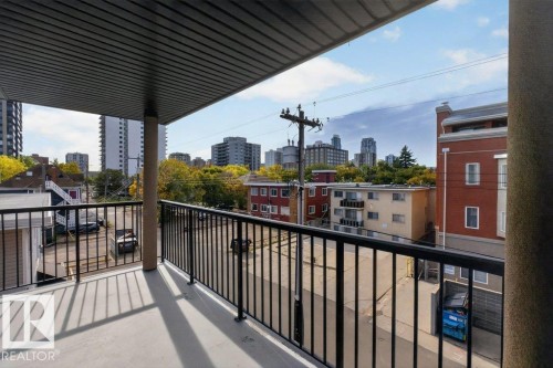 Balcony featuring concrete flooring and black metal railings, overlooking urban architecture - #306 10232 115 St Nw, Edmonton, AB 