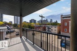 Balcony featuring concrete flooring and black metal railings, overlooking urban architecture - 