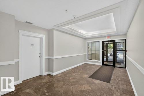 Recessed ceiling detail, crown molding, chair rail molding, full-light entry door, and patterned tile flooring - #306 10232 115 St Nw, Edmonton, AB 