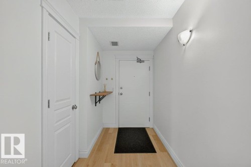 Light wood-finish flooring with white baseboards and walls - #306 10232 115 St Nw, Edmonton, AB 