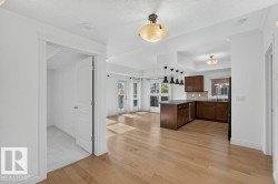 Hardwood flooring, kitchen island with pendant lighting, dark wood cabinetry, white trim, and a white interior door - 