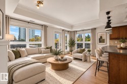 Open-concept living area with expansive windows, light wood-finish flooring, crown molding, and a kitchen island with pendant lighting - 