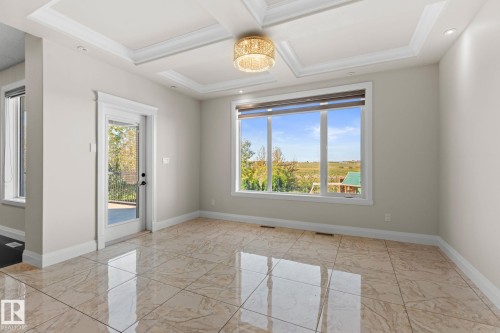 Tray ceiling with recessed lighting and a decorative chandelier, large window, glass-paneled door, and polished tile flooring - 229 Albany Drive Nw, Edmonton, AB 