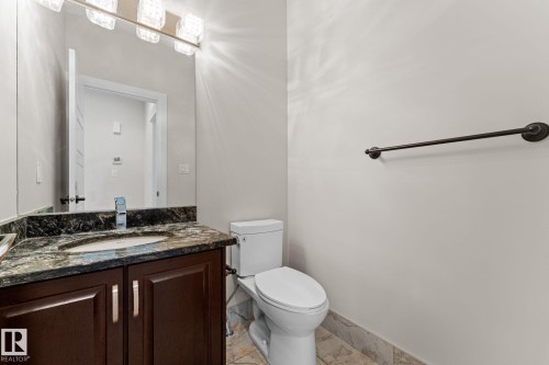 Dark wood-finish vanity with an undermount sink, stone countertop, and contemporary faucet - 229 Albany Drive Nw, Edmonton, AB 