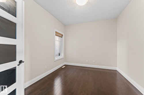 Dark wood-finish flooring with white trim, single window with natural light, modern ceiling light fixture, and a contemporary door with frosted glass panels - 229 Albany Drive Nw, Edmonton, AB 