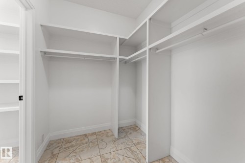 Custom closet system featuring multiple shelving units, hanging rods, and tile flooring - 229 Albany Drive Nw, Edmonton, AB 
